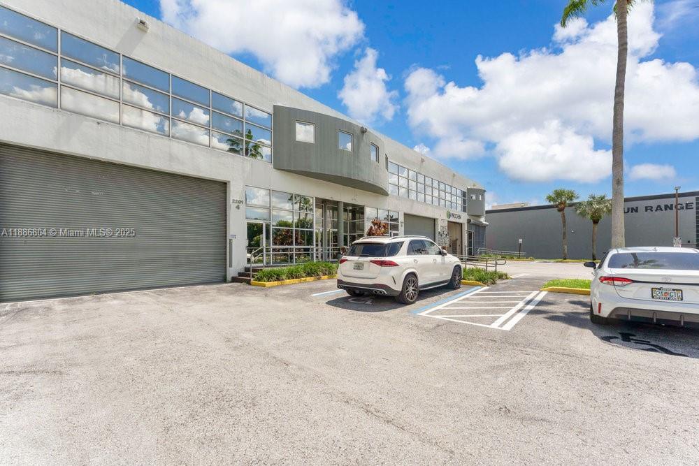 The exterior of a commercial building features a parking lot with two parked cars — 2201 NW 102nd Pl # 4A, Doral FL 33172, DORAL, FL
