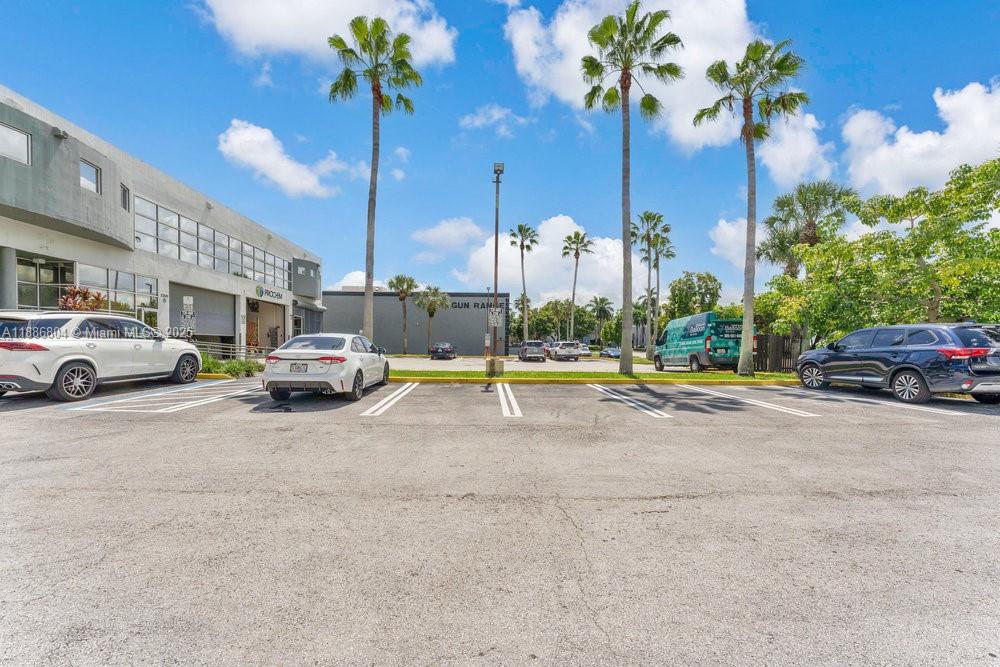 A parking lot with several cars sits in front of a building and palm trees — 2201 NW 102nd Pl # 4A, Doral FL 33172, DORAL, FL