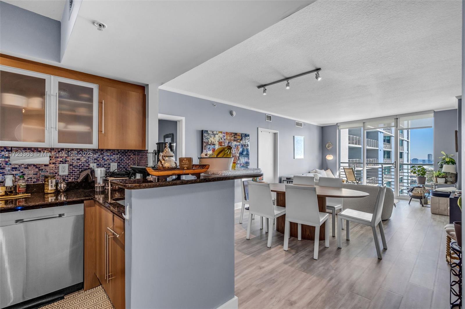 A kitchen with wood cabinets and granite countertops opens into a dining area and living room — 325 S Biscayne Blvd # 3726, Miami FL 33131, MIAMI, FL