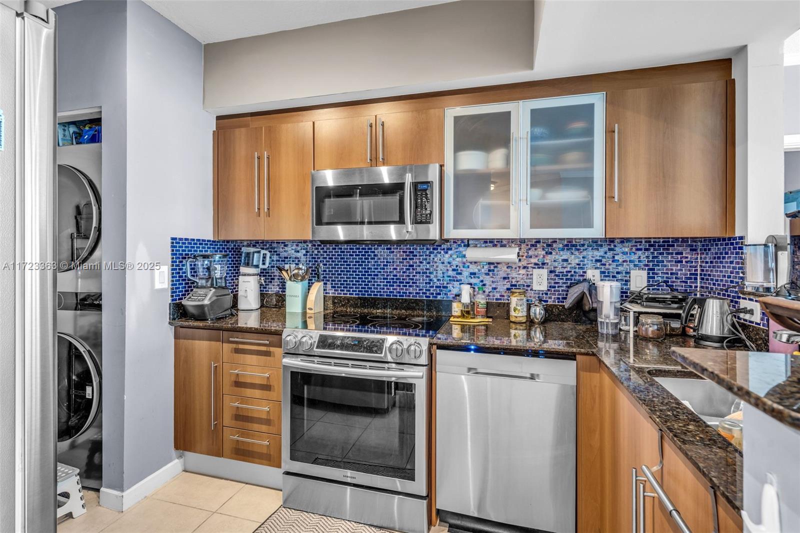A kitchen features wood cabinets, stainless steel appliances, a blue mosaic backsplash, and granite countertops — 325 S Biscayne Blvd # 3726, Miami FL 33131, MIAMI, FL