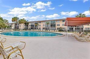 A swimming pool sits in front of a multi-story apartment building with lounge chairs nearby — 4500 N Federal Highway # 153, Lighthouse Point FL 33064, LIGHTHOUSE POINT, FL