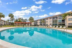 A large, round swimming pool sits in front of a multi-story apartment building with palms — 4500 N Federal Highway # 153, Lighthouse Point FL 33064, LIGHTHOUSE POINT, FL
