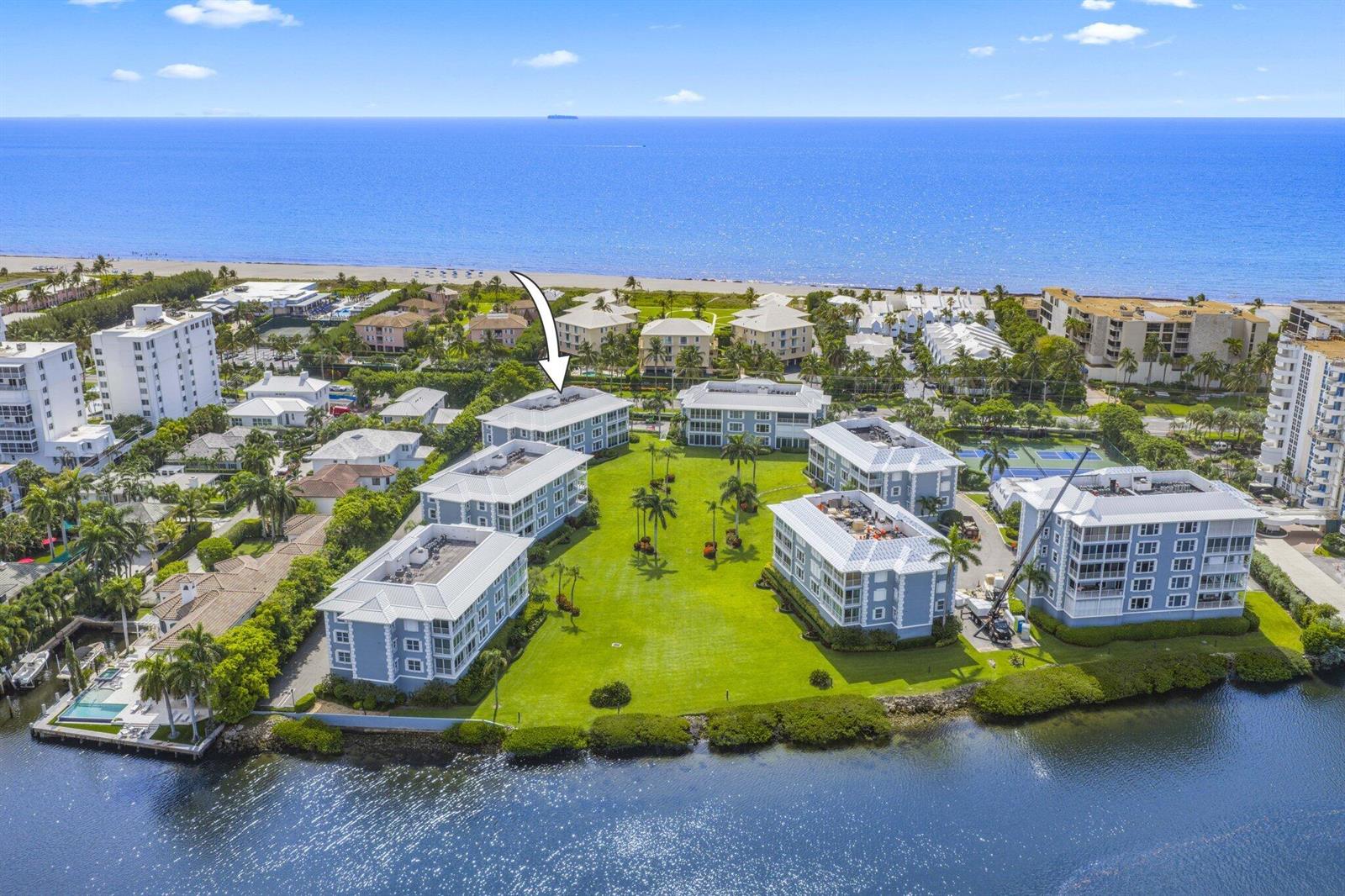 An aerial view shows several multi-story apartment buildings surrounding a large green lawn near water — 2150 S Ocean Boulevard # 3c, Delray Beach FL 33483, DELRAY BEACH, FL