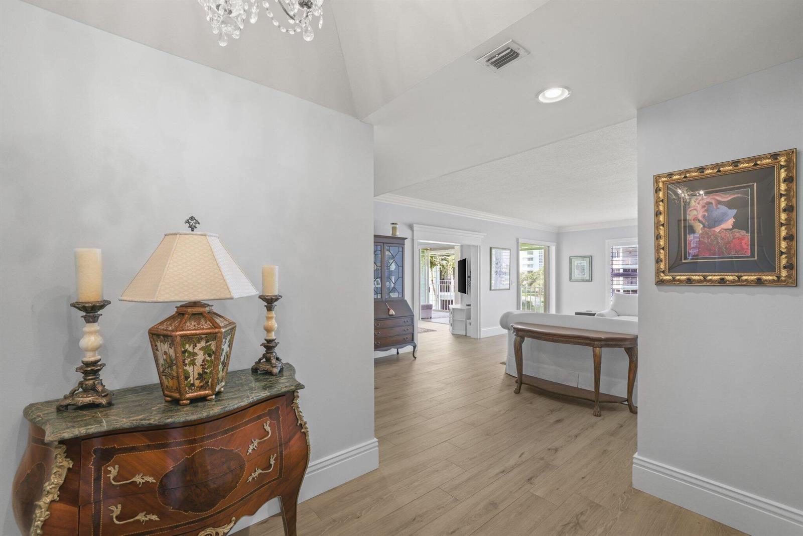 A foyer with a decorative chest and lamp leads into a living area with wood floors — 2150 S Ocean Boulevard # 3c, Delray Beach FL 33483, DELRAY BEACH, FL