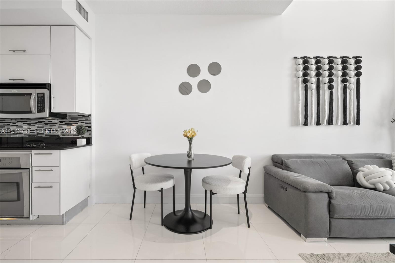 A dining area with a round black table and two chairs sits beside a kitchen — 60 SW 13th St # 2812, Miami FL 33130, MIAMI, FL