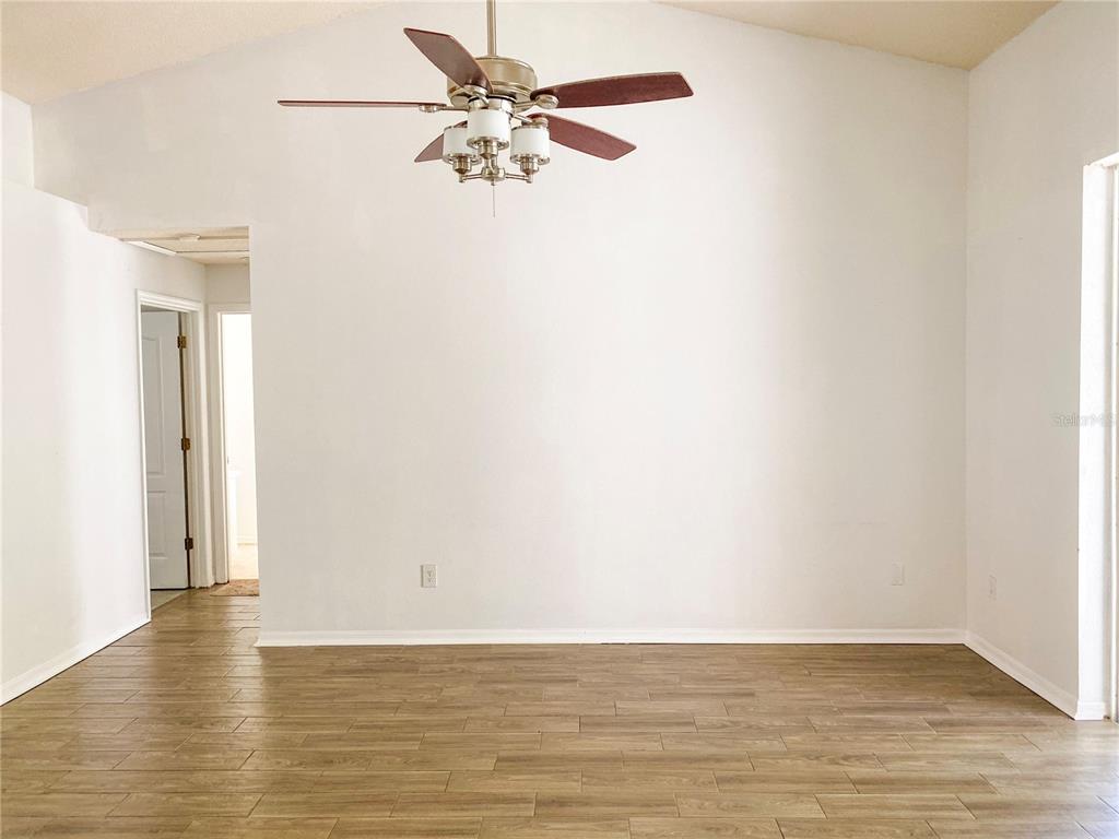 A room with light-colored walls, a vaulted ceiling, a ceiling fan, and wood-look flooring — 1004 BECKSTROM DRIVE, OVIEDO, FL