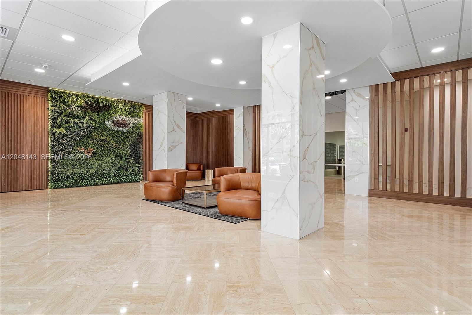 A modern lobby features marble columns, leather armchairs, and a large indoor vertical garden wall — SUNNY ISLES BEACH, FL