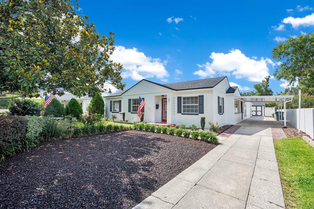 A white single-story house with a red front door, black shutters, and a concrete driveway — 607 KERNEYWOOD STREET, LAKELAND, FL