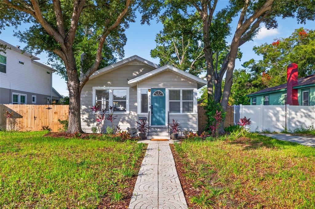 A single-story house with light siding, a teal front door, and large trees in front — 4624 IRIS STREET N, ST PETERSBURG, FL