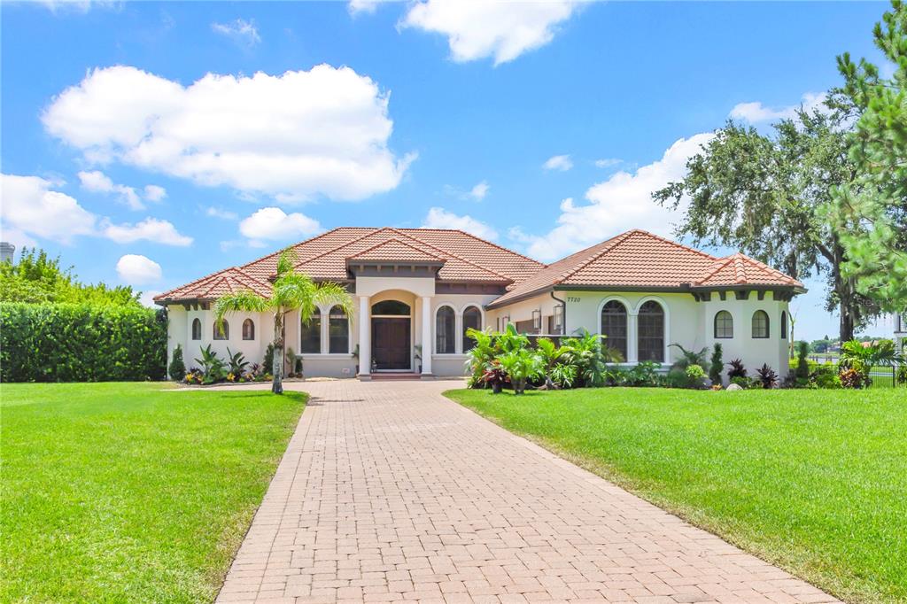 A single-story house with a tiled roof, arched windows, and a paved driveway — 7720 FICQUETTE ROAD, WINDERMERE, FL