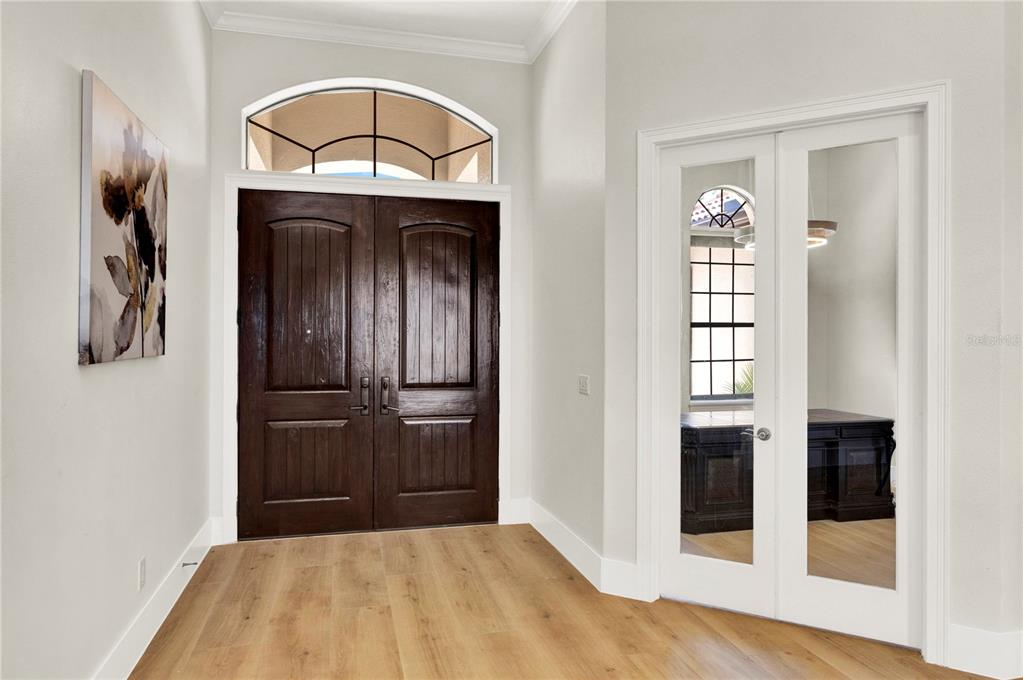 An entryway features light wood flooring, a dark wood double front door, and glass-paned French doors — 7720 FICQUETTE ROAD, WINDERMERE, FL
