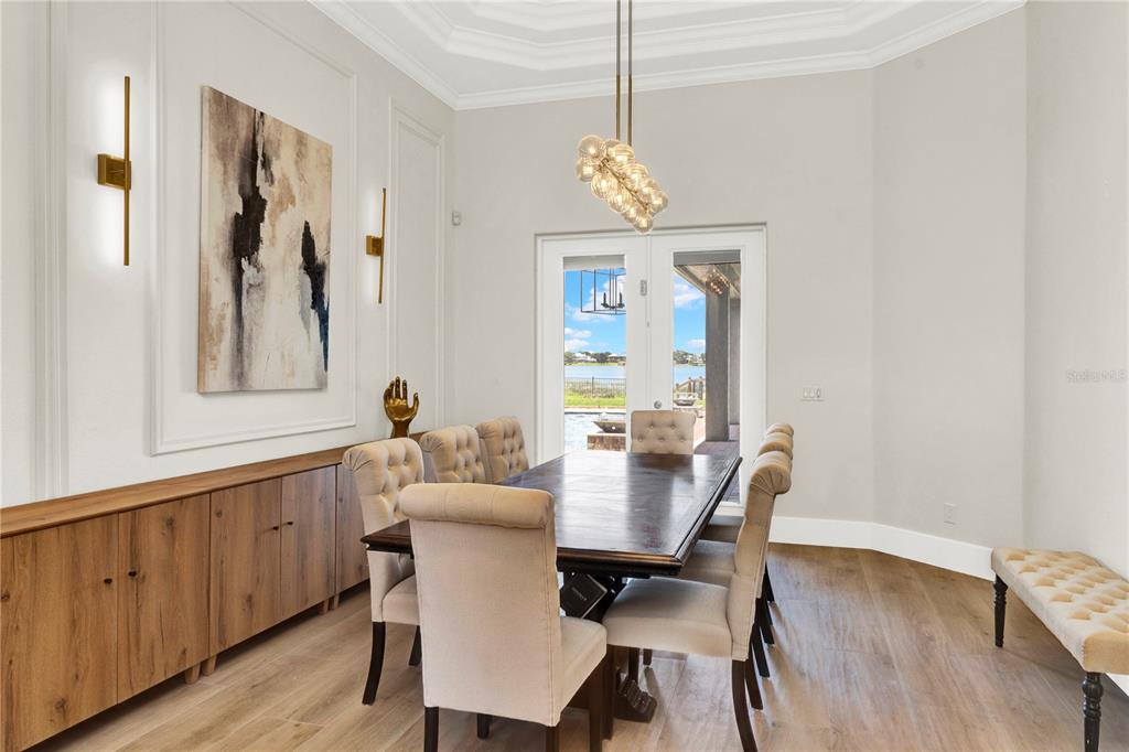 A dining room features a wooden table, upholstered chairs, a sideboard, and a lake view — 7720 FICQUETTE ROAD, WINDERMERE, FL