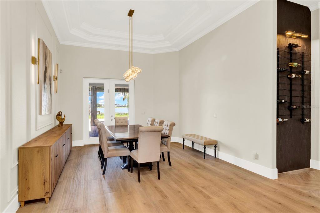 A dining room features a wooden table, upholstered chairs, a sideboard, and a wall-mounted wine rack — 7720 FICQUETTE ROAD, WINDERMERE, FL