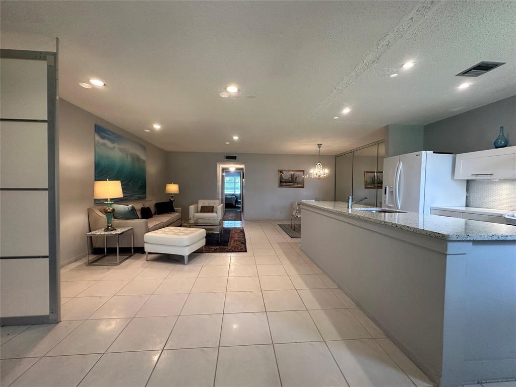 A living room and kitchen area feature light tile flooring, recessed lighting, and a breakfast bar — 14492 Canalview Drive # B, Delray Beach FL 33484, DELRAY BEACH, FL