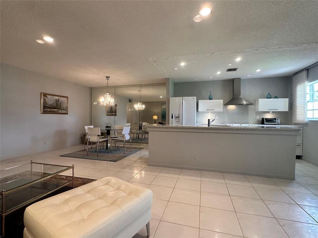 An open-concept kitchen and dining area features white cabinets, tile flooring, and mirrored walls — 14492 Canalview Drive # B, Delray Beach FL 33484, DELRAY BEACH, FL