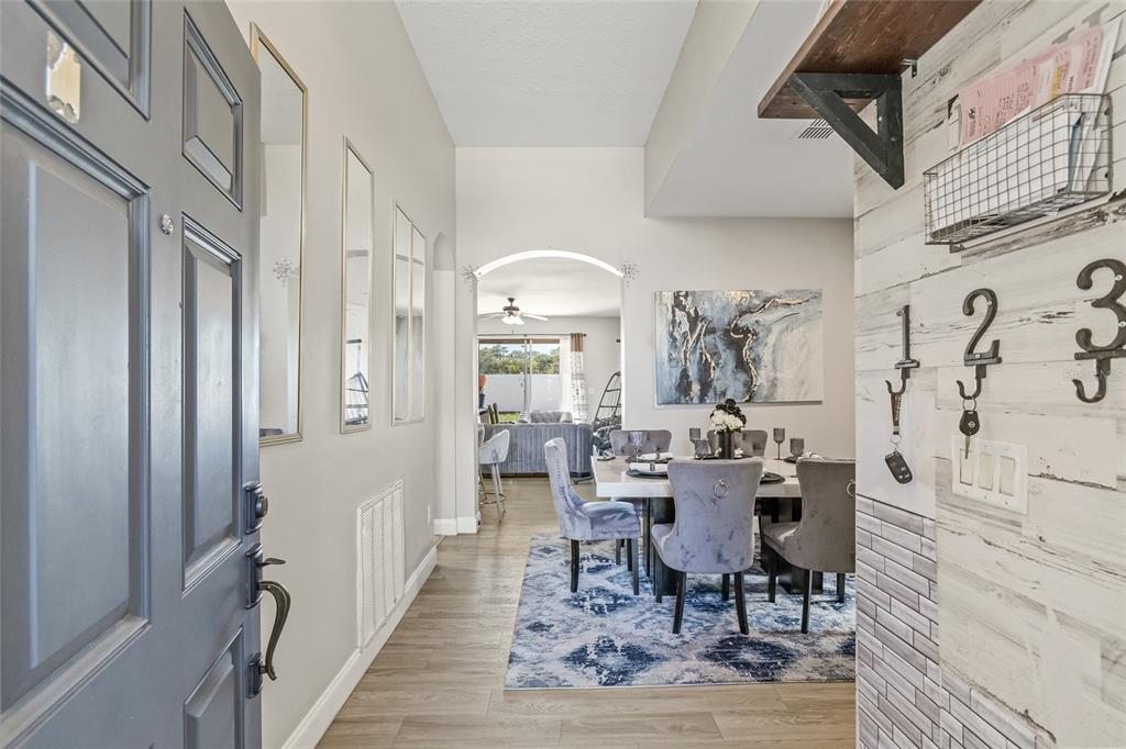 An entryway leads into a dining room featuring a blue patterned rug and gray chairs — 8521 SOUTHERN CHARM CIRCLE, BROOKSVILLE, FL