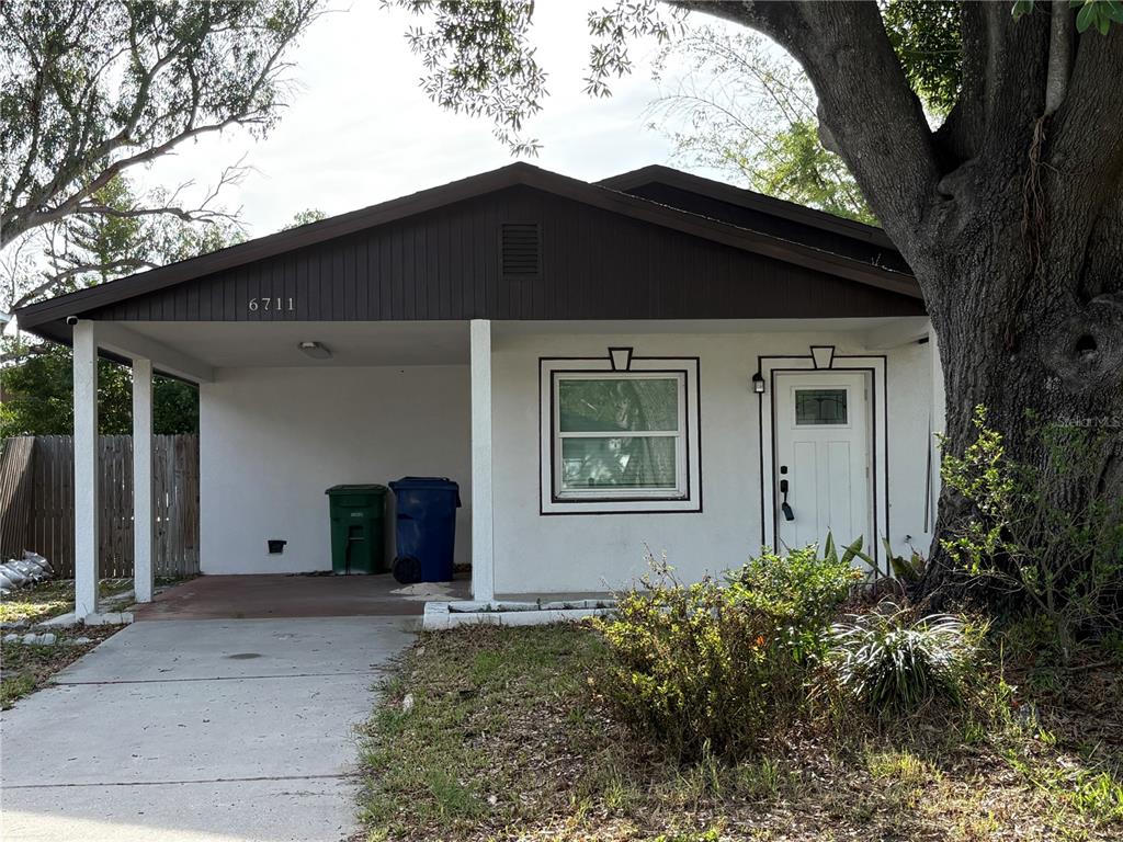 A single-story house with a carport, white stucco walls, and dark brown trim — 6711 S FAUL STREET, TAMPA, FL