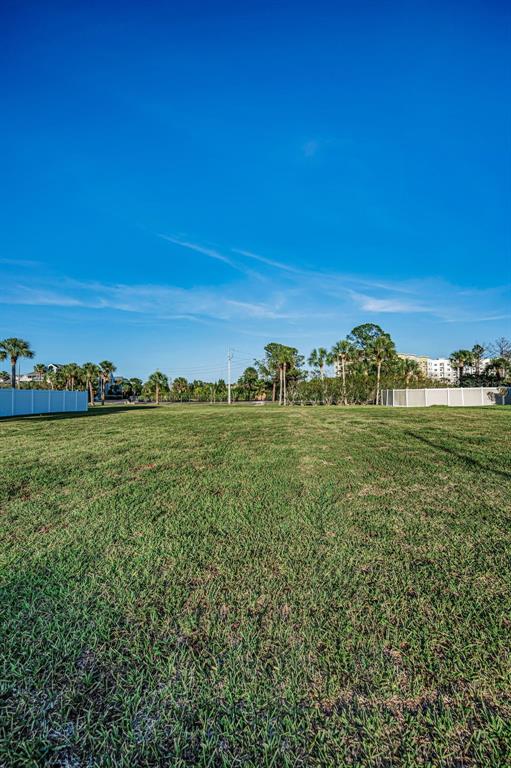 A wide, grassy vacant lot is enclosed by white vinyl fencing under a clear blue sky — Lot 59 JOBETH DRIVE, NEW PORT RICHEY, FL