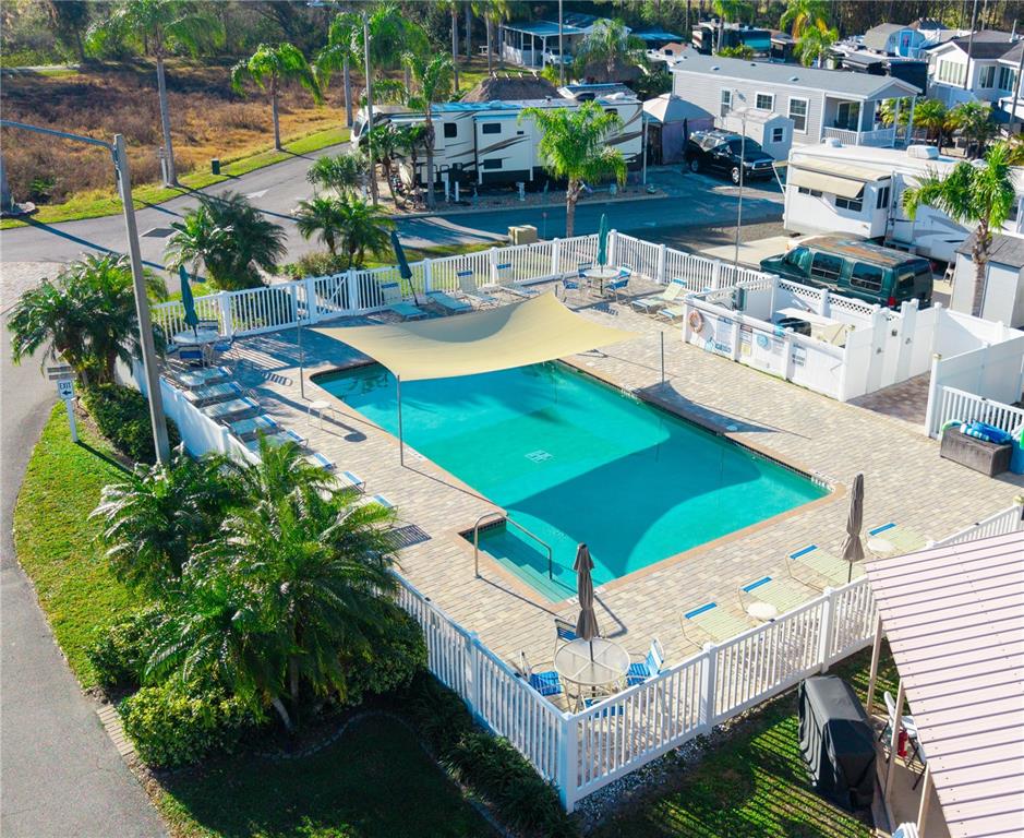 An aerial view shows a rectangular swimming pool with a shade sail and lounge chairs — 20300 LEONARD ROAD UNIT 78, LUTZ, FL