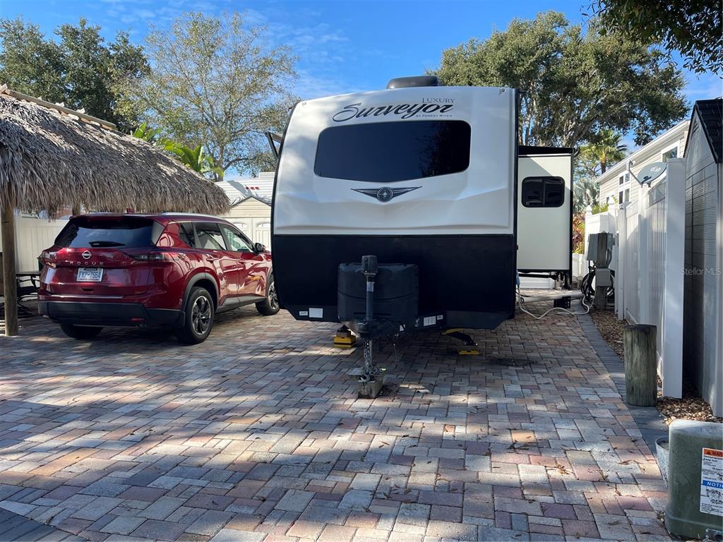 A red SUV is parked next to a Surveyor travel trailer on a paved driveway — 20300 LEONARD ROAD UNIT 78, LUTZ, FL