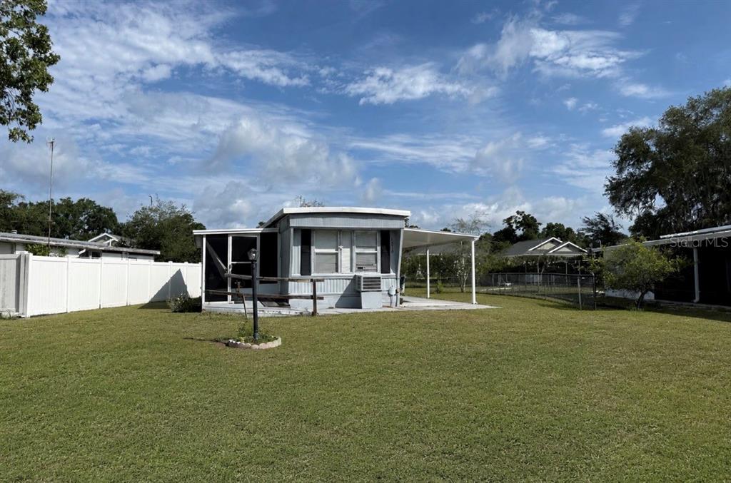 A single-story manufactured home with a screened porch and attached carport sits on a lawn — 1370 COUNTY DRIVE, TAVARES, FL