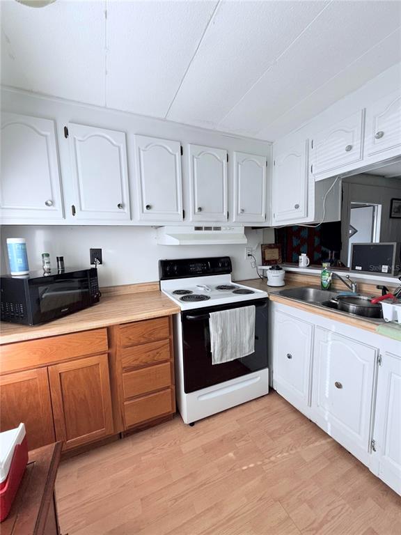A kitchen features white upper cabinets, wood lower cabinets, a white stove, and laminate countertops — 1370 COUNTY DRIVE, TAVARES, FL