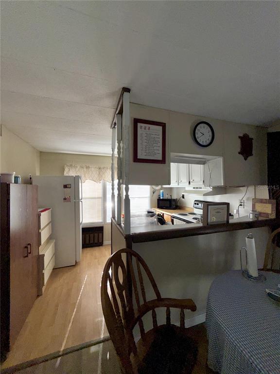 A kitchen with white cabinets, a breakfast bar, and a dining area with a chair — 1370 COUNTY DRIVE, TAVARES, FL
