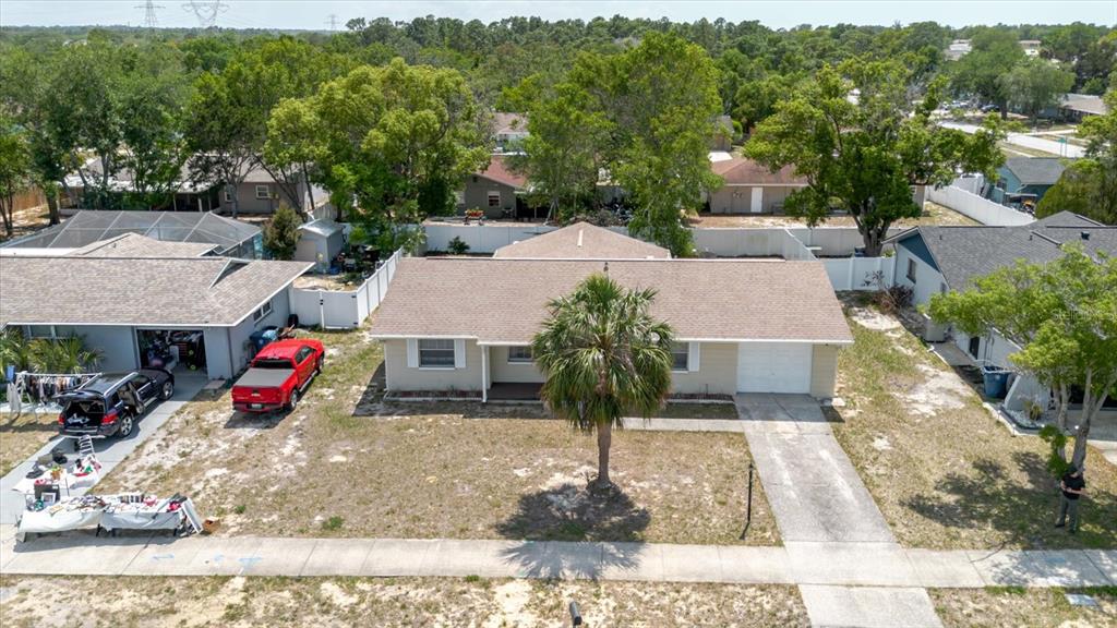 An aerial view shows a single-story house with a tan exterior, brown roof, and driveway — 12526 ELGIN BOULEVARD, SPRING HILL, FL