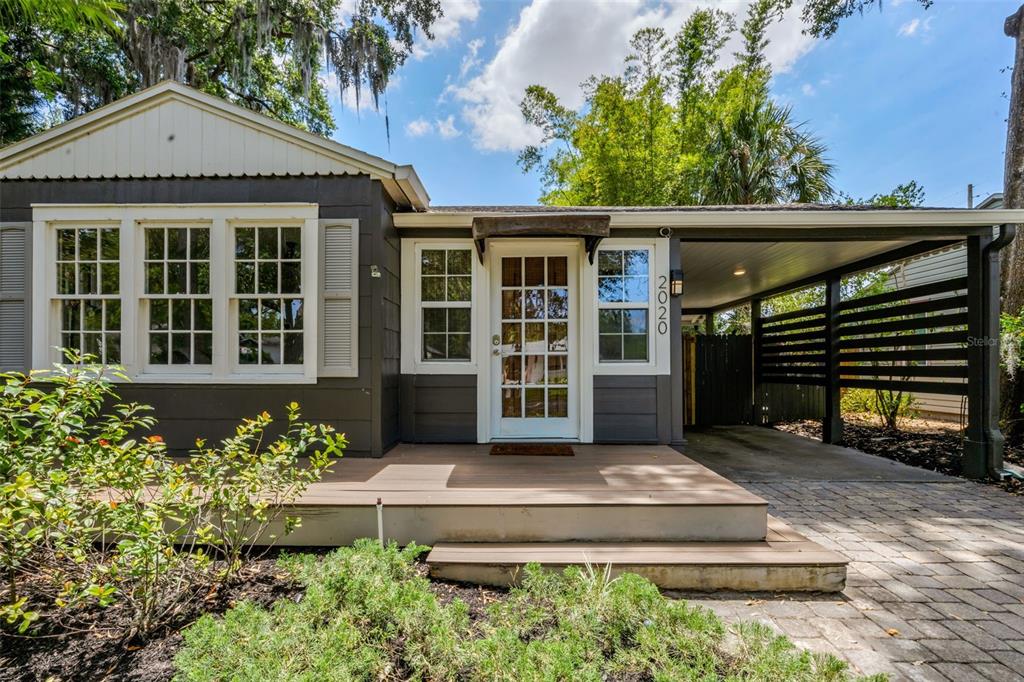 A single-story house with dark gray siding, a wooden front deck, and an attached carport — 2020 PALMER STREET, ORLANDO, FL