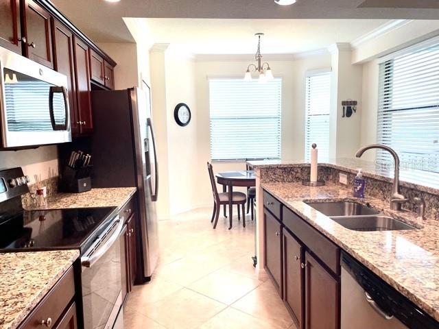 A kitchen with dark wood cabinets, granite countertops, and stainless steel appliances leads to a dining area — 16814 VARDON TERRACE UNIT 307, BRADENTON, FL