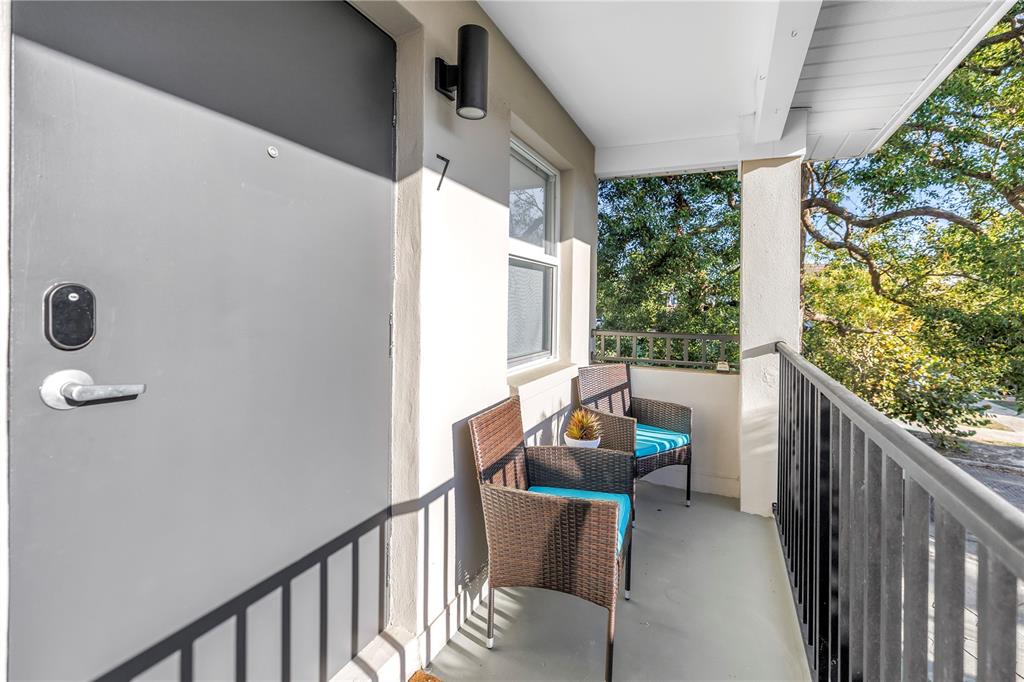 A balcony with two wicker chairs, a gray door, and a black metal railing — 224 6TH AVENUE N UNIT 7, ST PETERSBURG, FL