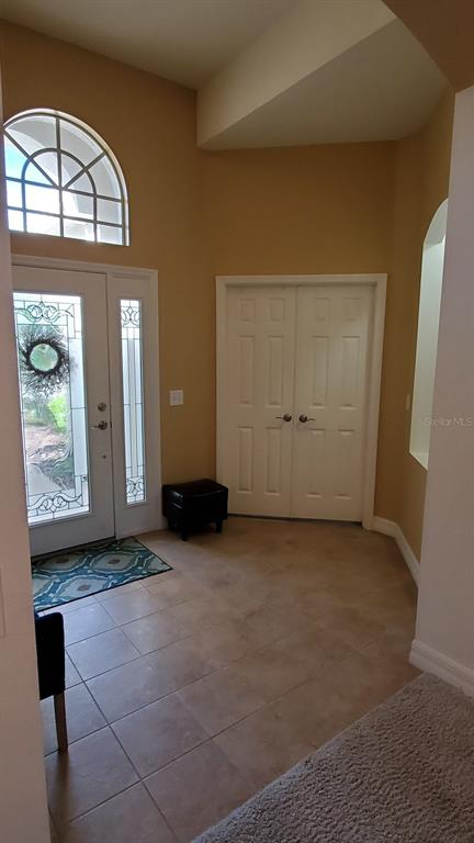 An entryway with tile flooring, a front door with glass panels, and double closet doors — 34421 BLUE ASH COURT, WESLEY CHAPEL, FL
