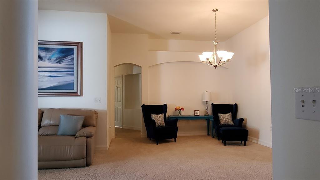 A living room features beige carpet, two dark blue armchairs, and a tan leather sofa — 34421 BLUE ASH COURT, WESLEY CHAPEL, FL