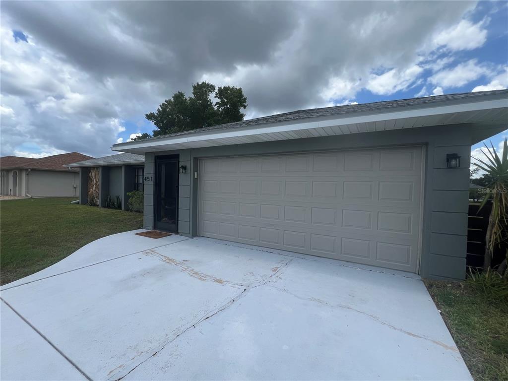 A gray house exterior features a two-car garage, a front entrance, and a concrete driveway — 451 RIO DE JANEIRO AVENUE, PUNTA GORDA, FL