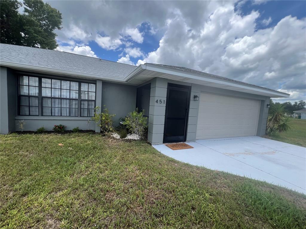 A single-story house features a gray exterior, a front door with a screen, and a garage — 451 RIO DE JANEIRO AVENUE, PUNTA GORDA, FL
