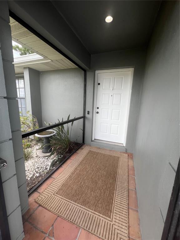 A covered entryway features a white door, a tiled floor, and a screened-in garden area — 451 RIO DE JANEIRO AVENUE, PUNTA GORDA, FL