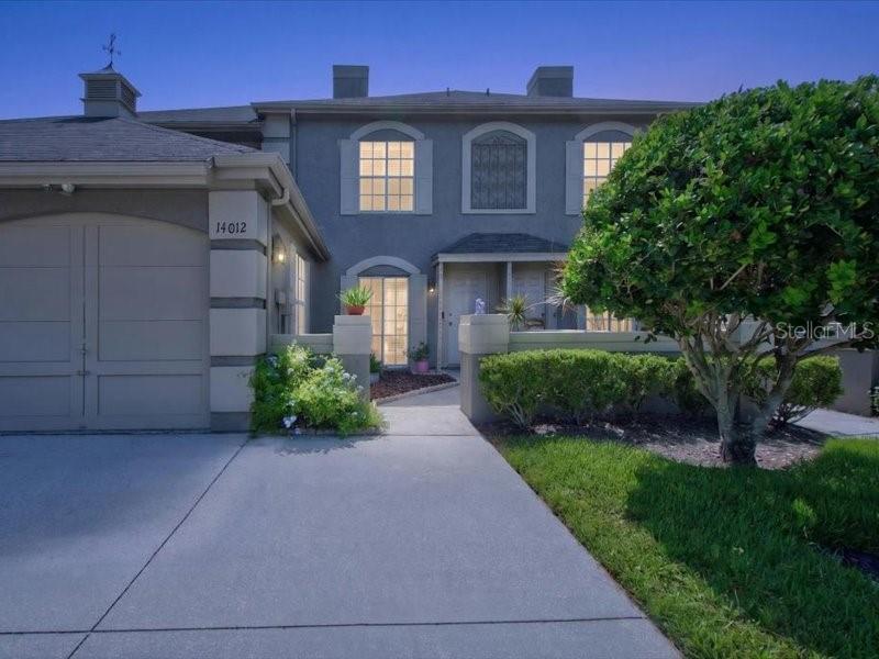 A two-story house exterior features a garage, a concrete driveway, and a manicured front lawn — 14012 NOTREVILLE WAY, TAMPA, FL
