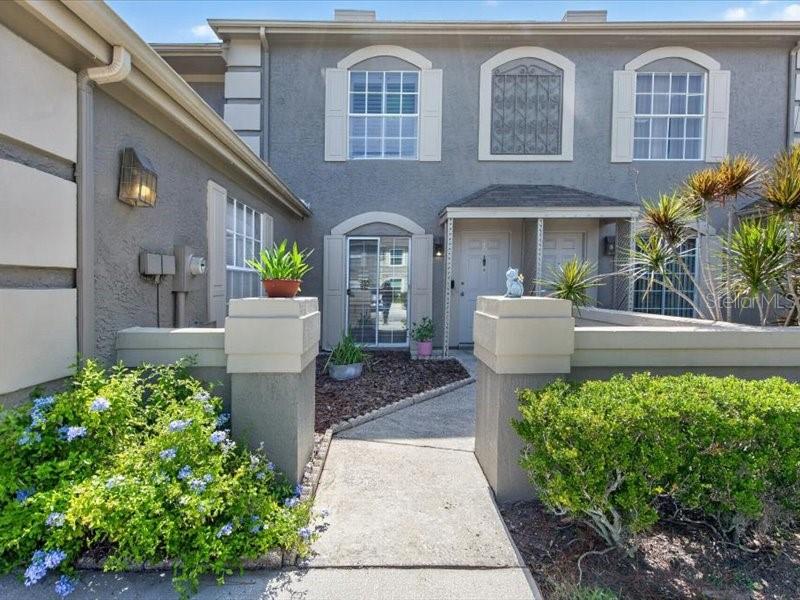 A two-story gray townhouse features a concrete walkway leading to a front entrance — 14012 NOTREVILLE WAY, TAMPA, FL