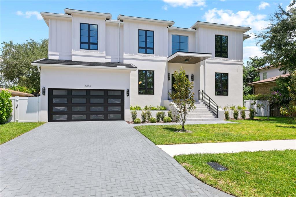 A two-story modern house features a white stucco exterior, dark window frames, and a garage — 5003 W POE AVENUE, TAMPA, FL
