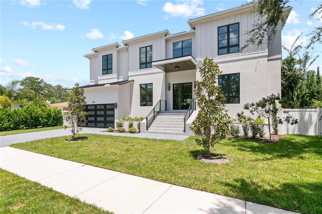 A two-story modern house with white siding, black-framed windows, and a front staircase — 5003 W POE AVENUE, TAMPA, FL