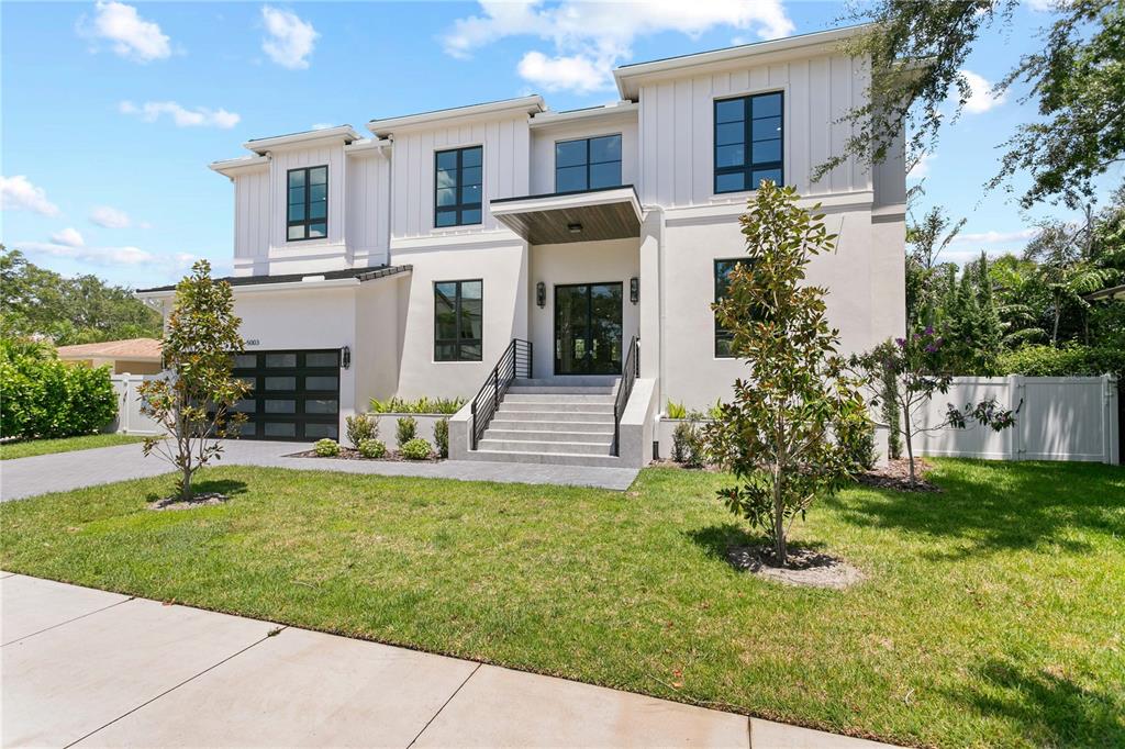 A modern two-story house with white vertical siding, large windows, and a raised front entrance — 5003 W POE AVENUE, TAMPA, FL