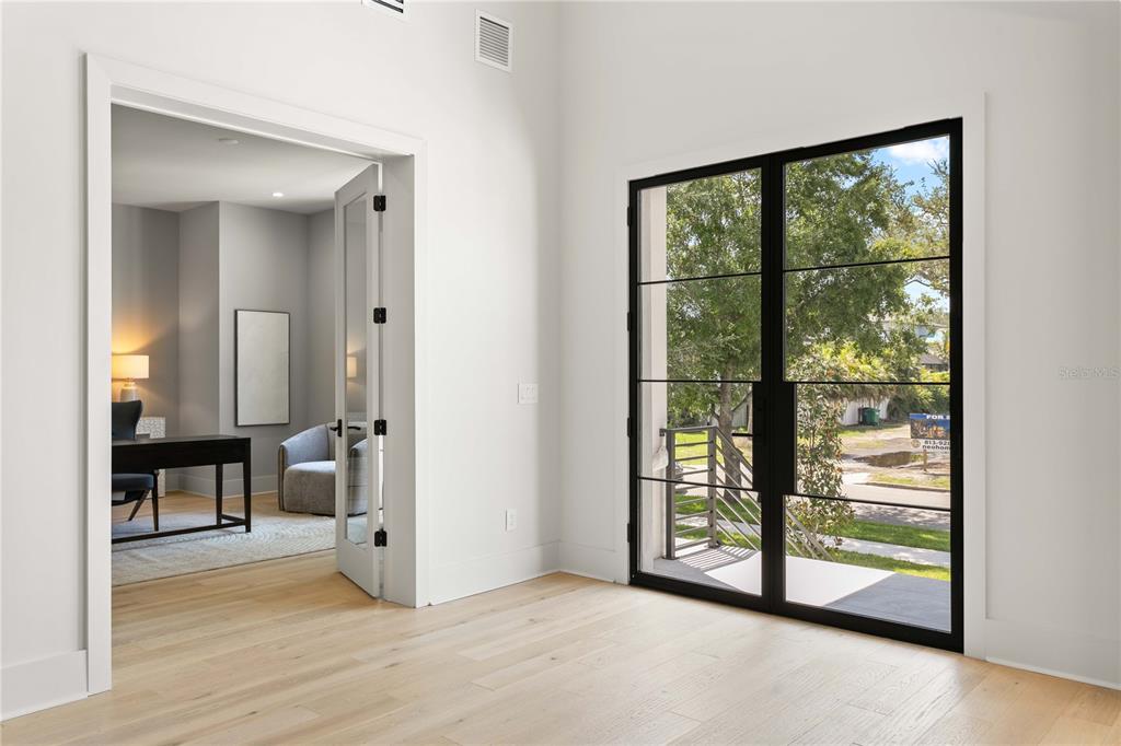 A room with light wood floors, a glass-paned double door, and an open doorway — 5003 W POE AVENUE, TAMPA, FL