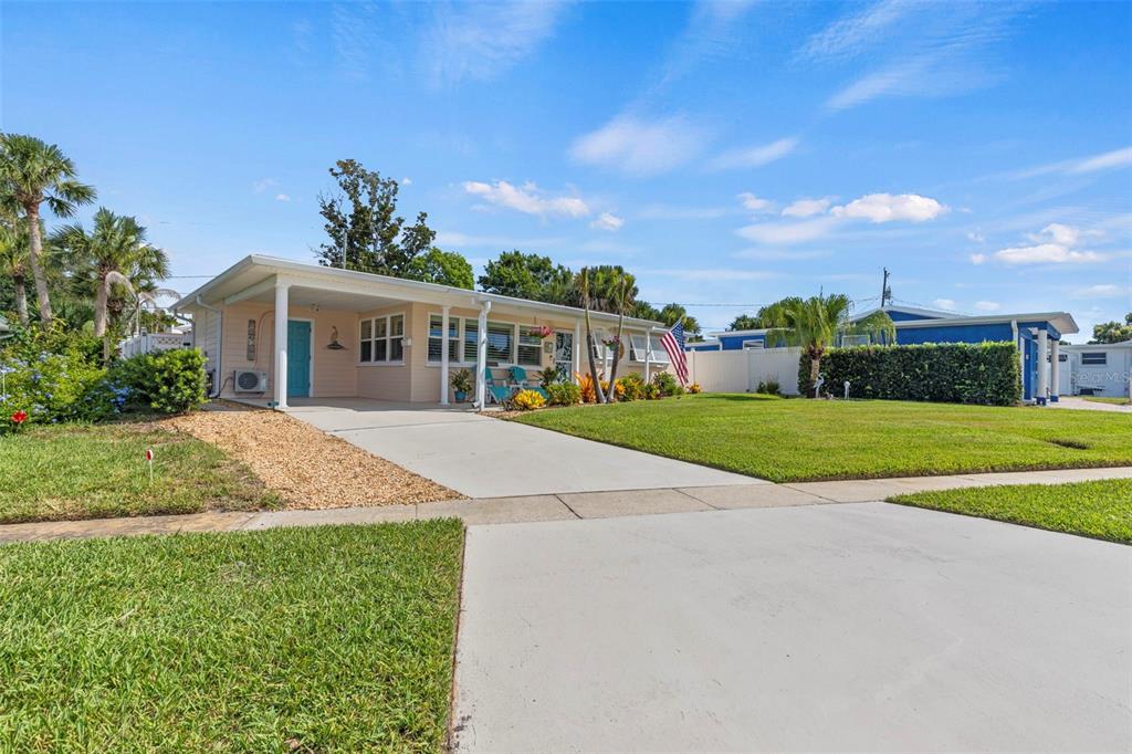 A light-colored single-story house with a carport, front lawn, and an American flag — 67 SEABREEZE DRIVE, ORMOND BEACH, FL