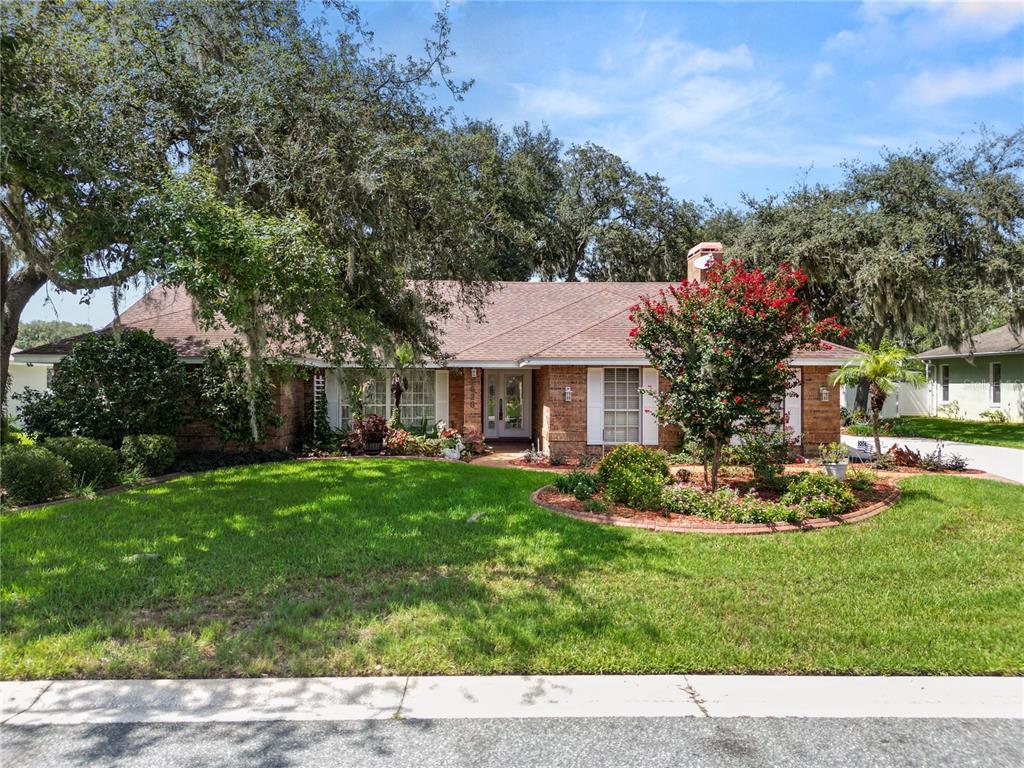A single-story brick house with a shingled roof, front lawn, and mature trees — 1626 SHERWOOD LAKES BOULEVARD, LAKELAND, FL