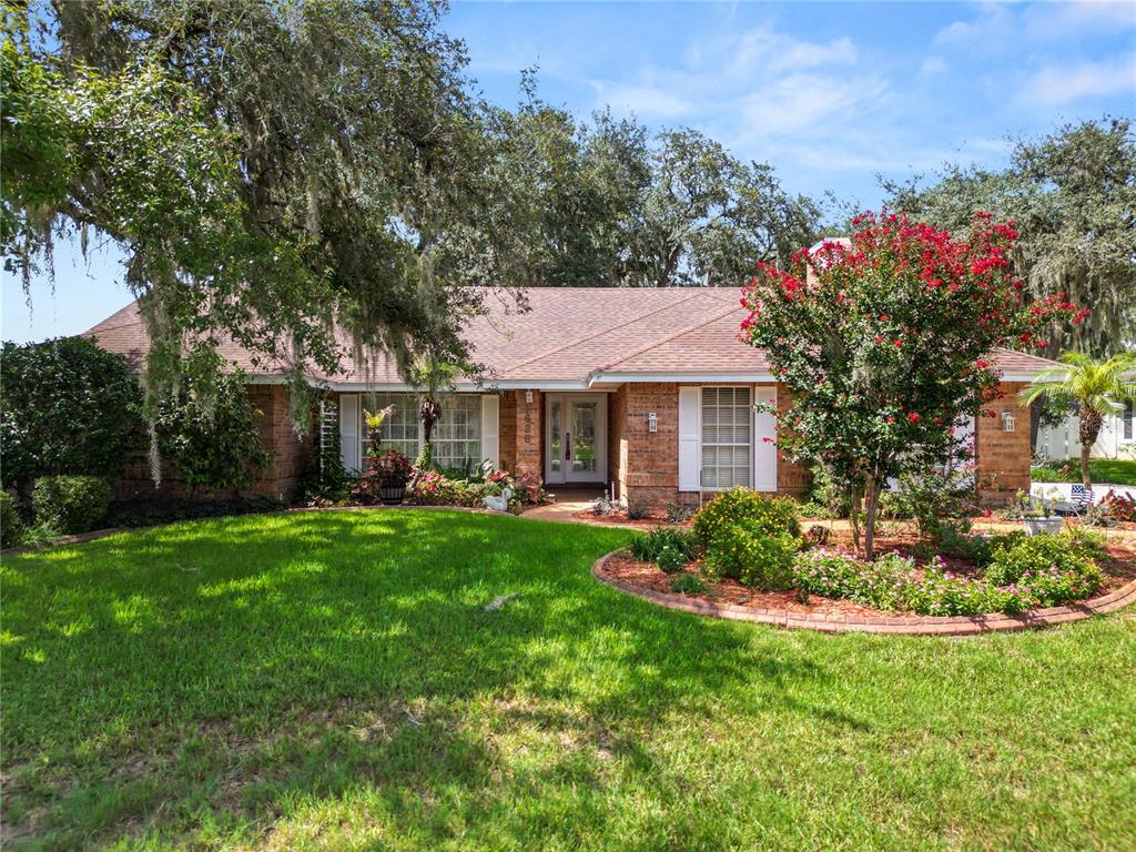 A single-story brick house with a front lawn, landscaping, and a large tree — 1626 SHERWOOD LAKES BOULEVARD, LAKELAND, FL