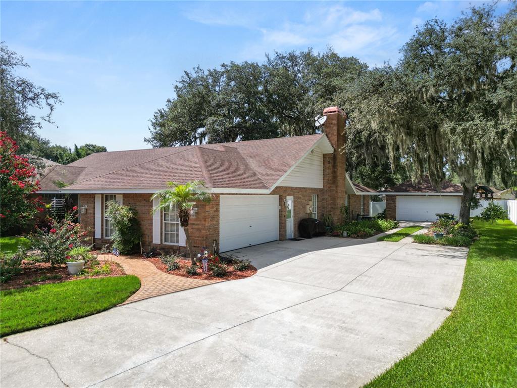 A brick house with a brown roof, a two-car garage, and a large concrete driveway — 1626 SHERWOOD LAKES BOULEVARD, LAKELAND, FL
