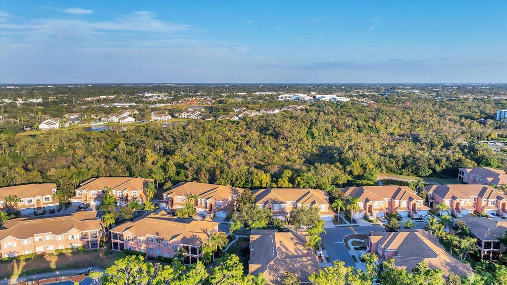 An aerial view shows multiple multi-story residential buildings surrounded by dense trees and vegetation — 5523 46TH COURT W, BRADENTON, FL