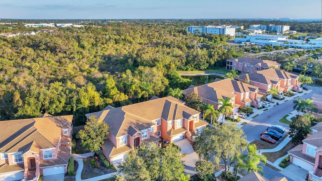 An aerial view shows several multi-story residential buildings with tile roofs near a wooded area — 5523 46TH COURT W, BRADENTON, FL