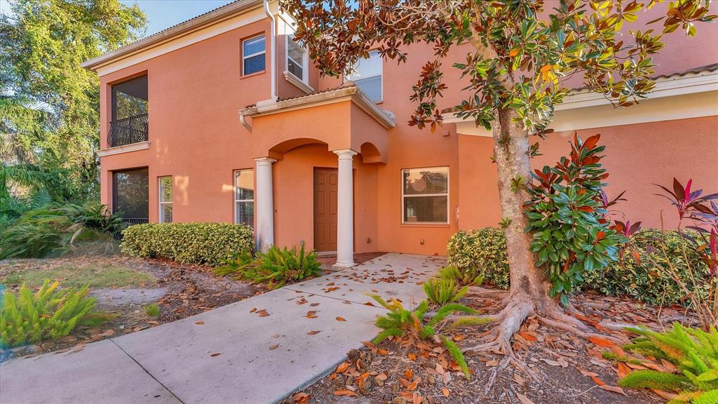 A two-story peach-colored building features a covered entryway with white columns and a walkway — 5523 46TH COURT W, BRADENTON, FL