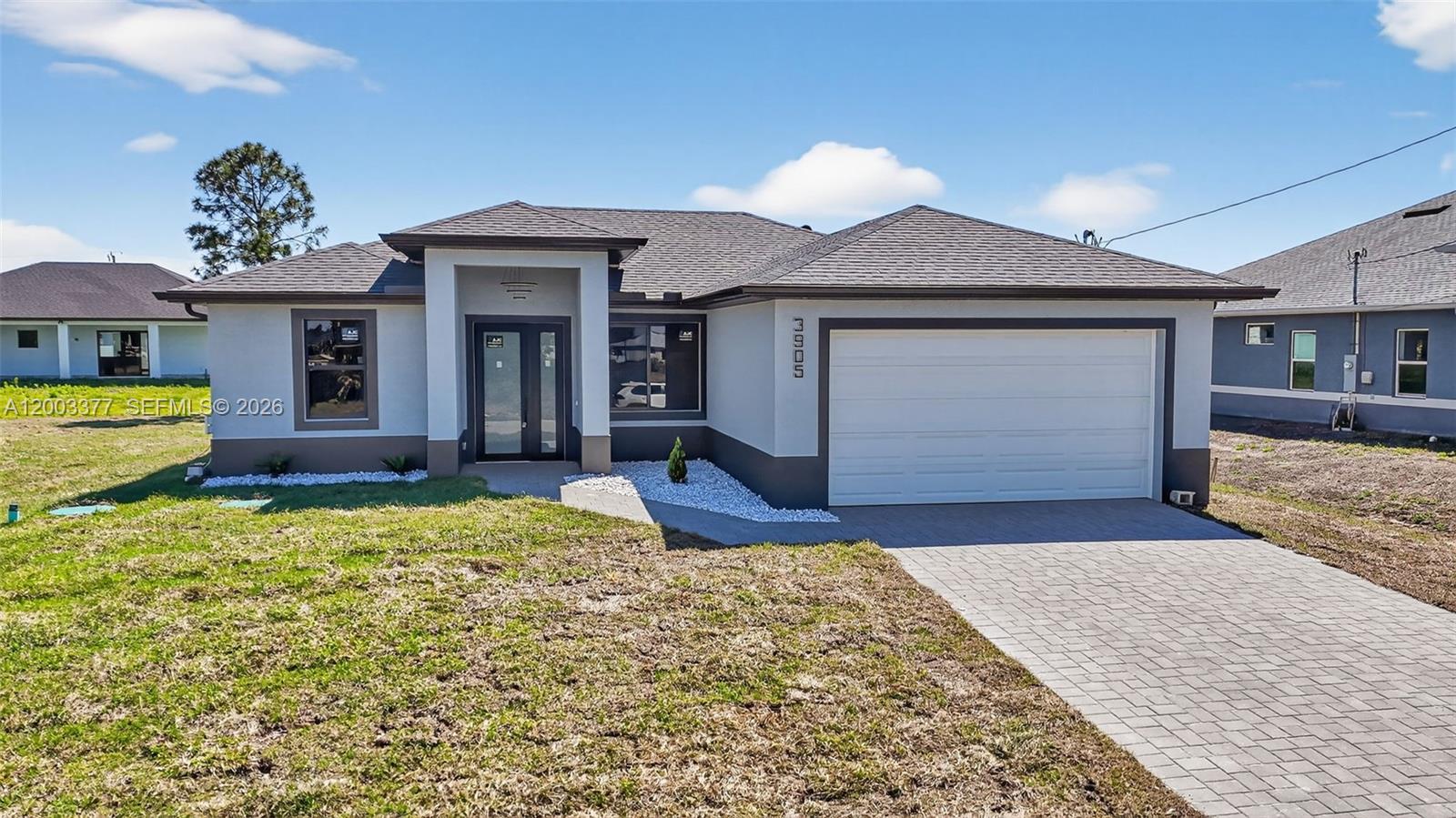 A single-story house with a white stucco exterior, a two-car garage, and a paved driveway — 3903 SW 11, Lehigh Acres FL 33976, LEHIGH ACRES, FL